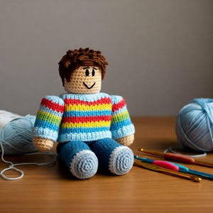 Puede incluir: Un juguete de crochet que representa a una persona con un suéter a rayas de arcoíris y jeans azules. El juguete está sentado sobre una superficie de madera con hilo y ganchos de crochet.