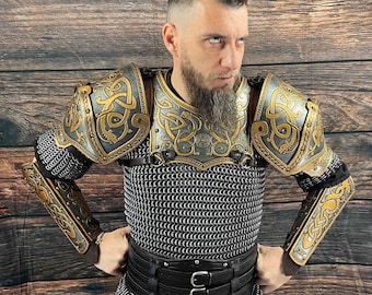 May include: A man wearing a chainmail shirt with a leather belt and gold-colored armor with intricate designs. The armor includes shoulder pads and arm guards.