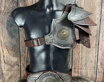 May include: A silver and brown leather armor set with a large circular plate on the chest and shoulder armor. The armor is displayed on a mannequin.
