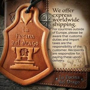 Puede incluir: Una etiqueta de cuero marr&oacute;n con el texto "La Fucina del Drago" y un dise&ntilde;o de yunque estilizado. La etiqueta est&aacute; unida a un fondo de cuero con una br&uacute;jula y texto sobre env&iacute;os a todo el mundo.