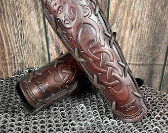Può includere: Un paio di bracciali in pelle marrone con intricati nodi celtici e disegni di draghi. I bracciali sono legati insieme con cinturini in pelle.