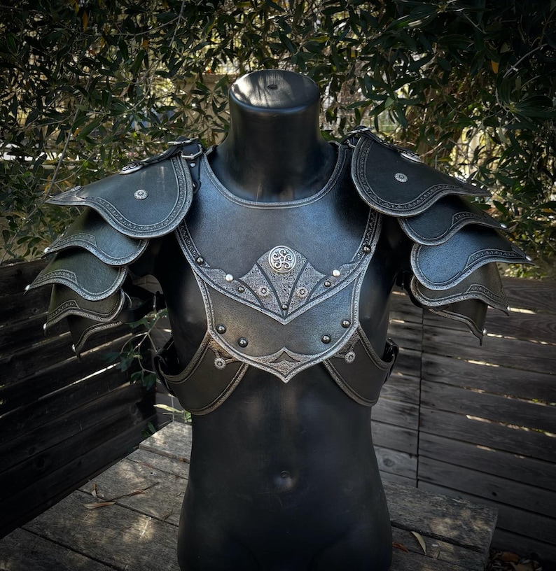 May include: Black and silver fantasy armor set, displayed on a mannequin. The chest piece and shoulder pauldrons are detailed with ornate silver accents and rivets. The armor is designed with layered plates and decorative edges, suggesting a medieval or fantasy theme.