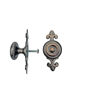 May include: Two antique bronze cabinet knobs with decorative backplates and a screw. One knob is round, the other is a decorative pull. The hardware has a distressed finish, suitable for furniture restoration or new builds.