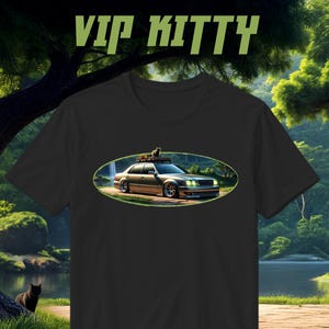 Puede incluir: Camiseta negra con un gráfico ovalado que representa un coche con un gato en el techo, sobre un fondo paisajístico. El texto "VIP KITTY" está impreso en verde encima del gráfico. La camiseta es de cuello redondo.