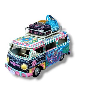 Peut inclure: Un van jouet en métal peint à la main, coloré, avec un porte-bagages sur le toit. Le van est décoré de fleurs, de volutes et de motifs géométriques dans des tons de rose, bleu, vert, jaune et noir. Le porte-bagages est chargé d'un sac bleu, d'une valise noire et d'un récipient jaune.
