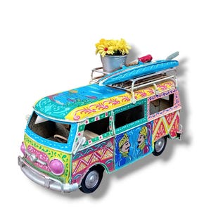 Peut inclure: Un van jouet en métal coloré peint à la main avec une planche de surf et des fleurs sur le toit. Le van est décoré de motifs complexes et de deux personnages en vêtements traditionnels.