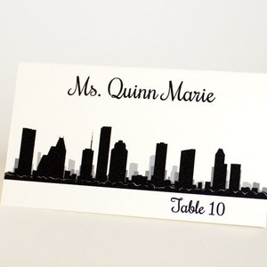 Tarjeta de lugar impresa del horizonte de Houston con el nombre del huésped y la mesa, elija la fuente y el color, llega doblada