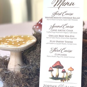 May include: A vertical white menu card featuring the text Menu, First Course, Watercress & Cheddar Salad, Second Course, Crisp Arctic Char, Grilled Beef Rib-Eye, Puff Pastry Tower, Third Course, Cupcakes, Jordan and Alicia, and 4.18.2025.