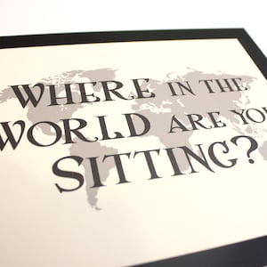 May include: A framed print with a world map graphic in gray and the text "WHERE IN THE WORLD ARE YOU SITTING?" in black. The print has a cream-colored background and a black border.