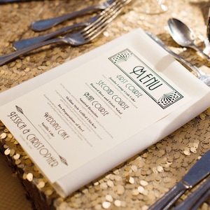 May include: A wedding menu with a green and gold art deco design. The menu lists the courses: Jumbo Lump Crab Cake, Roasted Beet and Fris&eacute;e Salad, Saut&eacute;ed Branzino, Sicilian Style Grilled Chicken, and Wedding Cake. The menu is on a gold sequin tablecloth.