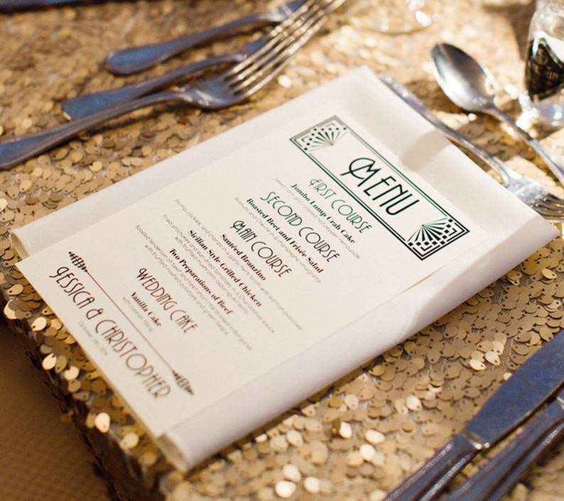 May include: A wedding menu with a green and gold art deco design. The menu lists the courses: Jumbo Lump Crab Cake, Roasted Beet and Fris&eacute;e Salad, Saut&eacute;ed Branzino, Sicilian Style Grilled Chicken, and Wedding Cake. The menu is on a gold sequin tablecloth.