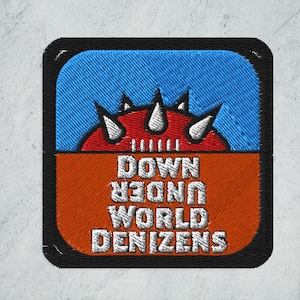 May include: A black and orange embroidered patch with a red and white spiky design and the text "DOWN UNDER WORLD DENIZENS".