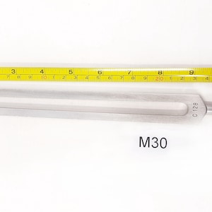May include: A silver tuning fork with the text "C128" on the handle. The tuning fork is 7 inches long and is labeled "M30".