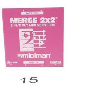 May include: A pink box with the text "MERGE 2x2" and "2 IN/2 OUT MIDI MERGE BOX" printed on it. The box also has a logo with the number "2" and the text "midiman" printed on it.