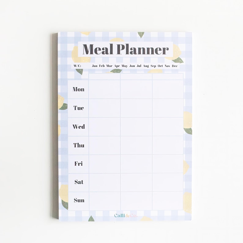 Op de afbeelding: Een witte maaltijdplanner met een blauw-wit geruit patroon en citroenillustraties. De planner heeft een sectie voor elke dag van de week en een rij voor elke maand van het jaar. De tekst "Meal Planner" staat bovenaan de pagina.