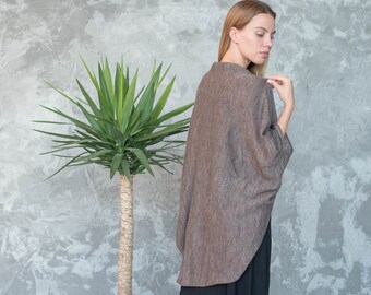May include: A brown linen cardigan with a relaxed fit and a slightly longer back hem. The cardigan is worn over a black skirt.