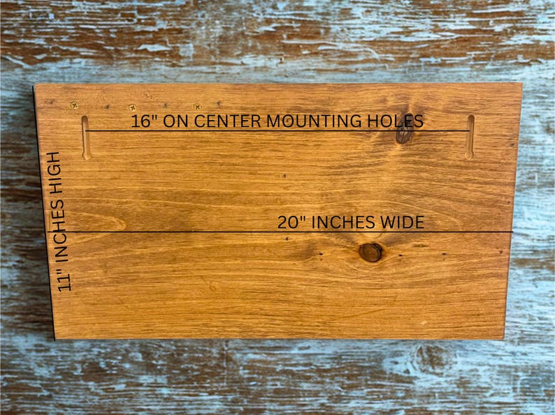 Pu&ograve; includere: Una tavola di legno macchiato con il testo "16" ON CENTER MOUNTING HOLES", "20" INCHES WIDE" e "11" INCHES HIGH". La tavola &egrave; rettangolare con una finitura marrone chiaro e venature del legno visibili. Il testo &egrave; nero.