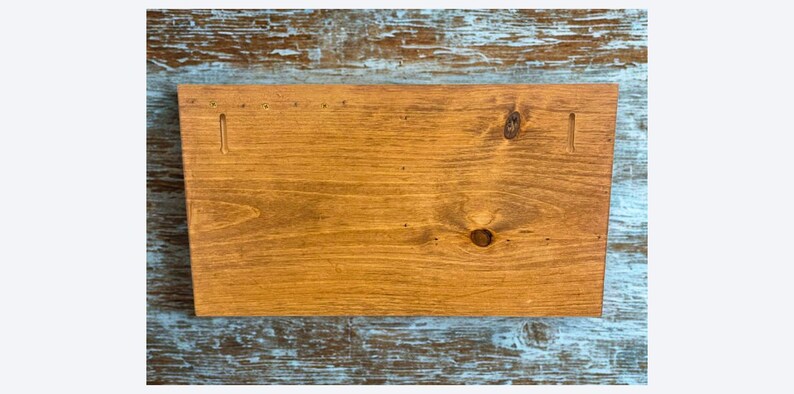 Pu&ograve; includere: Un cartello rettangolare in legno con una calda macchia marrone dorata. La venatura del legno &egrave; visibile e ci sono due fessure intagliate vicino alla parte superiore per appenderlo. Il cartello &egrave; su uno sfondo blu e bianco usurato.