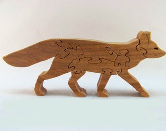May include: A wooden fox puzzle with intricate cutouts. The fox is standing on all four legs with its tail curled behind it. The puzzle is made of light brown wood and is a great way to challenge your brain and have fun.