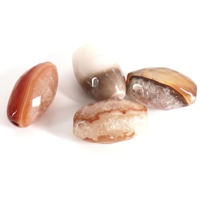 May include: Four polished, oval-shaped agate beads with natural banding and crystalline centers. The beads display earthy tones of burnt orange, cream, white, and translucent brown, featuring smooth, glossy surfaces and visible internal mineral textures.