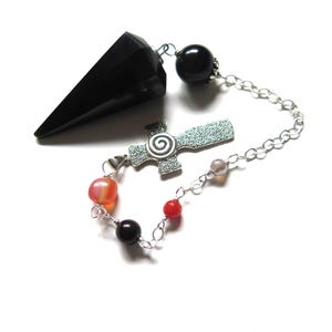 May include: A black crystal pendulum with a silver chain and colorful beads. The pendulum has a faceted, cone-like shape. The chain is connected to a silver cross with a spiral design.