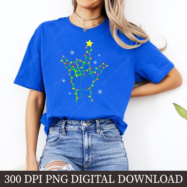 May include: Royal blue t-shirt featuring a hand sign design made of Christmas lights, a yellow star, and snowflakes. The design is a festive representation of the phrase "I love you" in American Sign Language. The text "300 DPI PNG DIGITAL DOWNLOAD" is at the bottom.