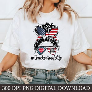 May include: A white t-shirt with a graphic of a woman's hair in a bun with an American flag bow. The woman is wearing sunglasses with a heart and a semi-truck in the lenses. The text "#Truckerswifelife" is below the graphic.