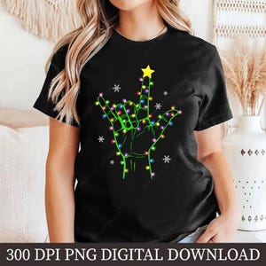 May include: Black t-shirt featuring a green hand in the ASL sign for "I love you", decorated with colorful Christmas lights and a yellow star. The shirt also has white snowflake accents. The text "300 DPI PNG DIGITAL DOWNLOAD" is at the bottom.