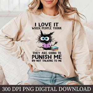May include: A beige sweatshirt with a black cat reading a book. The text on the sweatshirt reads "I love it when people think they are going to punish me by not talking to me".