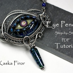 Puede incluir: Un colgante de alambre plateado envuelto alrededor de una cuenta de vidrio azul y verde en forma de ojo. El colgante está unido a una cadena de plata con cuentas azules. La imagen incluye el texto "Eye Pendant Step-by-Step PDF Tutorial by Kaska Firor".