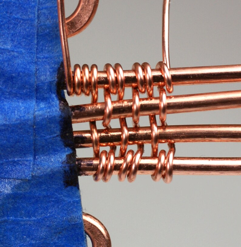 May include: Close-up of a copper wire weaving technique, showing the intricate pattern of the woven wires. The wires are woven together in a grid-like pattern, creating a strong and durable structure.