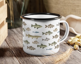 May include: White enamel mug with a black rim, decorated with various fish illustrations in shades of green, brown, and blue. The mug has a white handle and is set on a wooden surface. A perfect gift for fishing enthusiasts.