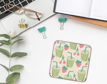 May include: Square coaster featuring a pattern of green smoothies, strawberries, and cherries on a beige backdrop. The coaster is on a white surface with a laptop, glasses, and stationery.