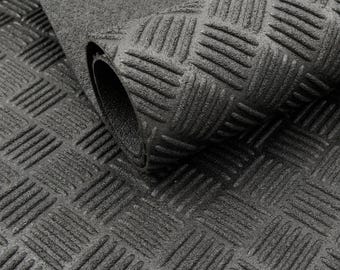 May include: A rolled-up, dark gray rubber mat with a diamond plate pattern. The mat is textured with raised, diagonal lines creating a non-slip surface. The image shows the mat partially rolled, revealing the underside.