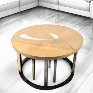 Puede incluir: Una mesa de centro redonda de madera con una base de metal negro. La tapa de la mesa tiene un inserto de vidrio transparente.