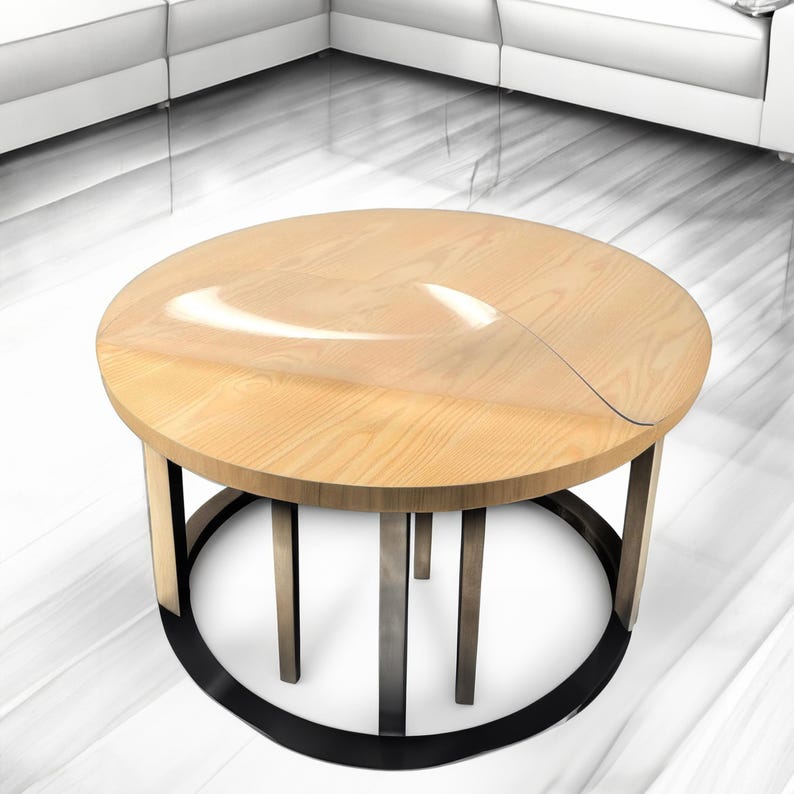 Puede incluir: Una mesa de centro redonda de madera con una base de metal negro. La tapa de la mesa tiene un inserto de vidrio transparente.