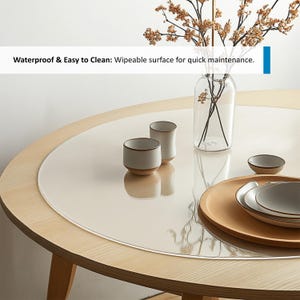 Puede incluir: Un protector de mesa redondo transparente con un borde ligeramente elevado, colocado sobre una mesa de madera clara. El protector est&aacute; dise&ntilde;ado para proteger la superficie de la mesa de ara&ntilde;azos y derrames. El texto "Waterproof & Easy to Clean: Wipeable surface for quick maintenance." es visible en la imagen.