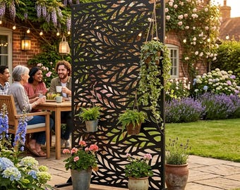 May include: A tall, rectangular black metal privacy screen featuring a laser-cut leaf pattern. The screen is freestanding with a sturdy base and includes multiple hanging hooks that hold various potted plants in metal and ceramic containers.