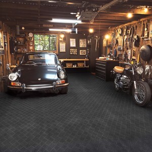 May include: A classic black car and a black motorcycle are positioned inside a garage with wooden walls. The garage is illuminated with various tools and equipment displayed on the walls, creating a classic automotive and motorcycle theme.