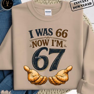 Puede incluir: Sudadera beige con el texto "I WAS 66 NOW I'M 67" en marr&oacute;n y azul marino. El n&uacute;mero 67 es grande y estilizado, con dos manos abiertas debajo. La sudadera tiene cuello redondo y mangas largas. "Instant Download" est&aacute; en la esquina superior derecha.