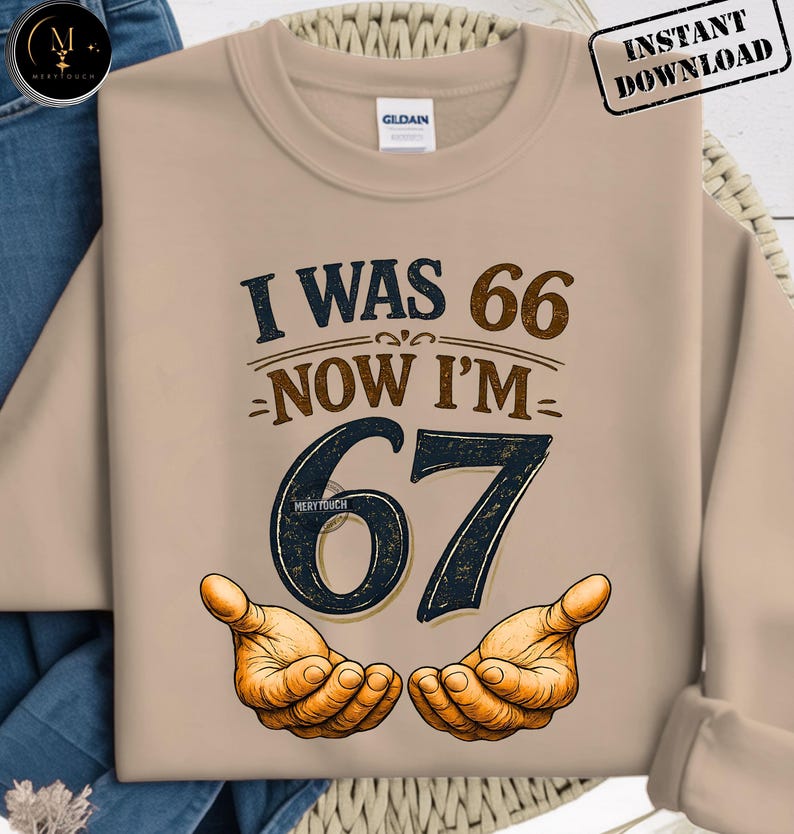 Puede incluir: Sudadera beige con el texto "I WAS 66 NOW I'M 67" en marr&oacute;n y azul marino. El n&uacute;mero 67 es grande y estilizado, con dos manos abiertas debajo. La sudadera tiene cuello redondo y mangas largas. "Instant Download" est&aacute; en la esquina superior derecha.