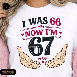 Puede incluir: Camiseta blanca con el texto "I WAS 66 NOW I'M 67" en negro y rojo. El dise&ntilde;o incluye dos manos y formas de coraz&oacute;n. Las palabras "DIGITAL DESIGN ONLY - NO PHYSICAL ITEM" est&aacute;n en la parte inferior.