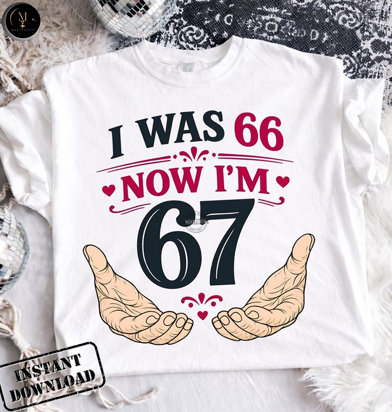 May include: White t-shirt with the text "I WAS 66 NOW I'M 67" in black and burgundy. The design includes two open hands and decorative hearts. The shirt is a birthday-themed product.