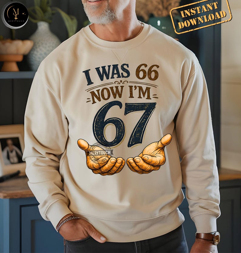 Puede incluir: Sudadera beige con el texto "I WAS 66 NOW I'M 67" en azul marino y marr&oacute;n. El n&uacute;mero 67 es grande y azul oscuro. El dise&ntilde;o incluye ilustraciones de manos. Las palabras "Instant Download" est&aacute;n en la esquina superior derecha.