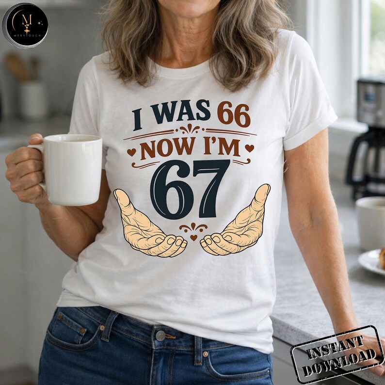 Puede incluir: Camiseta blanca con el texto "I WAS 66 NOW I'M 67" en marr&oacute;n y azul marino. El dise&ntilde;o incluye dos manos y corazones. La persona lleva una taza blanca.