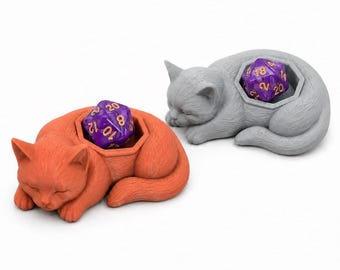 May include: Two sleeping cat-shaped containers, one orange and one gray, each featuring a hollow hexagonal compartment on the back. Inside each compartment sits a purple twenty-sided die with gold-colored numbers clearly visible on the faces.