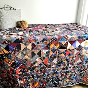 May include: A colorful quilt made from repurposed neckties. The quilt is made up of a patchwork of different colored and patterned ties, creating a unique and eye-catching design.