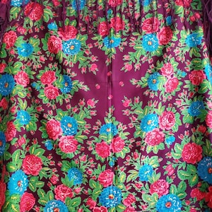 以下が含まれることがあります： 赤、青、緑の花柄が特徴の、ブルゴーニュ色のショール。 ショールはフリンジエッジと詳細なデザインで、伝統的なテキスタイルパターンを示しています。