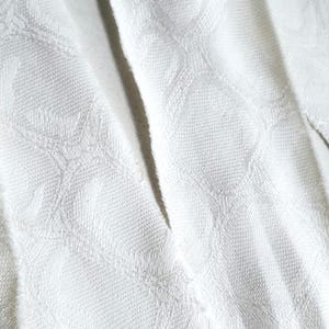 May include: White fabric with a diamond pattern woven into the material.