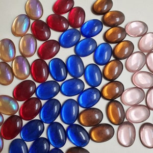 May include: Assortment of colourful glass tiles in various shapes and sizes, including round, oval, and rectangular. The tiles are arranged in a diagonal pattern on a white surface.